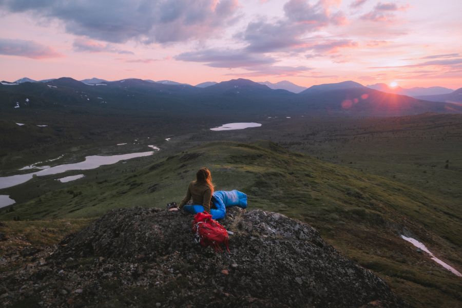 A woman watches the summer sun set at midnight to the north of Bonneville Lakes near Whitehorse