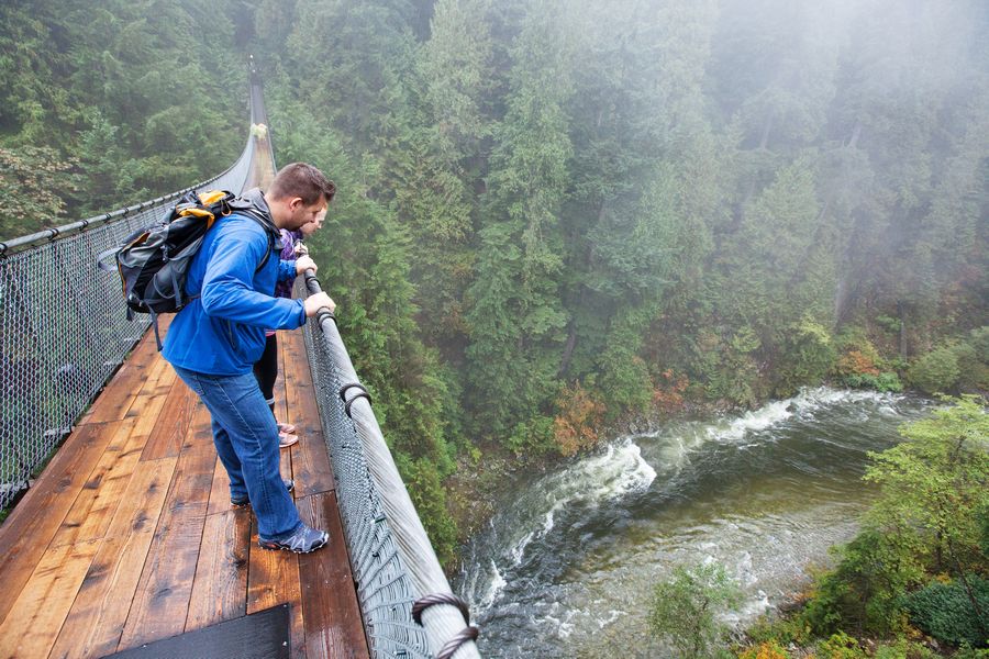 Wandelaars kijken over de rand van de Capilano Suspension Bridge in British Columbia.