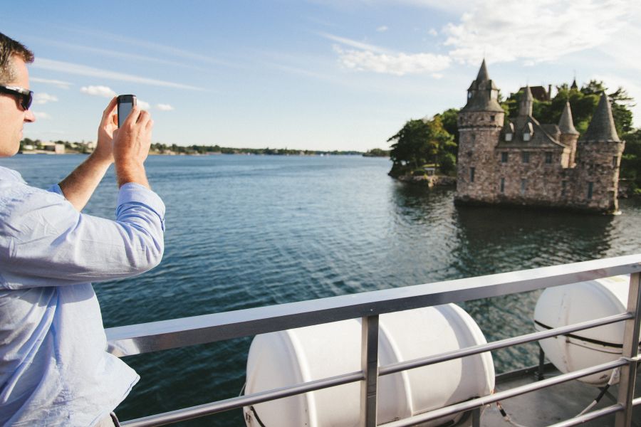 Passagier maakt foto van kasteel tijdens 1000 Islands cruise in Oost-Canada.