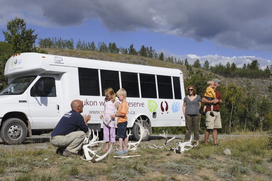 Mensen voor een bus van de Yukon Wildlife Preserve Tour in de Yukon in Canada.