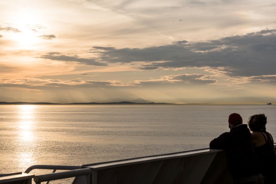 Mensen kijken naar zonsondergang vanaf het dek van BC Ferries in British Columbia in Canada.