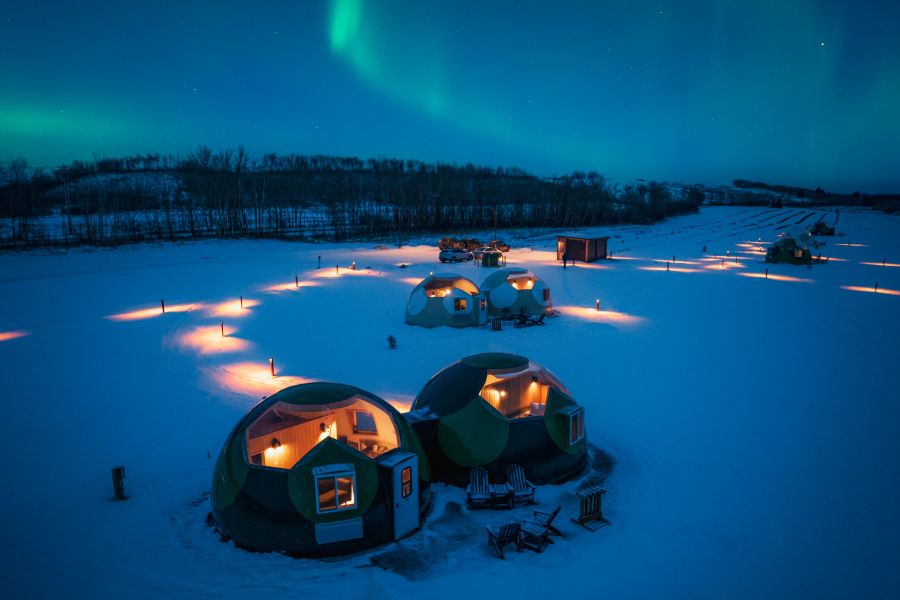 Buitenaanzicht van de Sky Domes bij Métis Crossing met noorderlicht op de achtergrond in Canada
