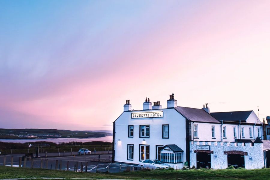 Het Causeway Hotel in Bushmills met een zonsondergang op de achtergrond