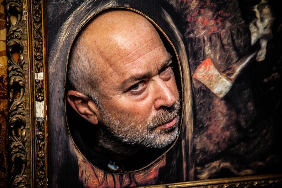 Een acteur van Ghostbus Tour achter een schilderij verstopt