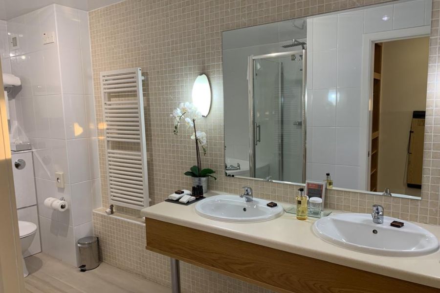 Badkamer van het Bayview Hotel in Bushmills met uitzicht op de wastafel en grote spiegel