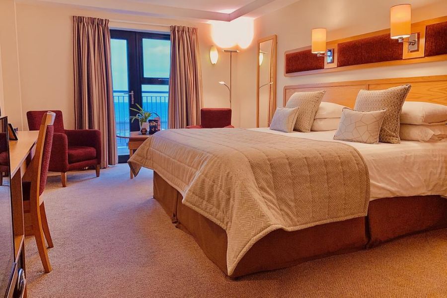 Een tweepersoonskamer in het Bayview Hotel in Bushmills met wit dekbedovertrek en grijze plaid