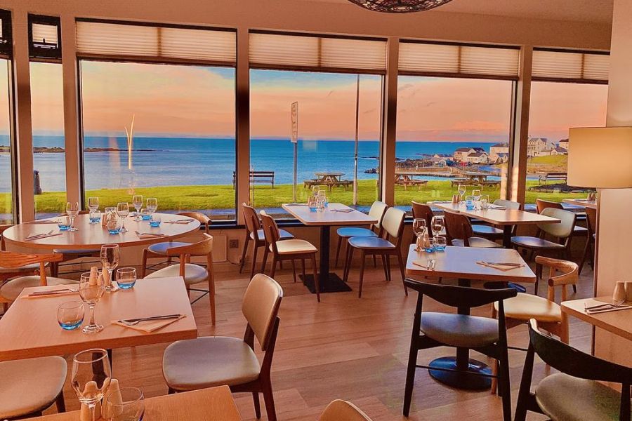 Het restaurant van het Bayview Hotel in Bushmills met uitzicht op het water tijdens zonsondergang