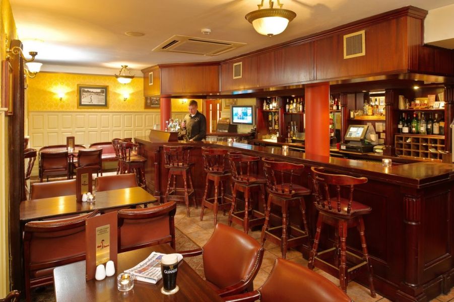 Een bar waar hoge houten barstoelen tegenaan staan