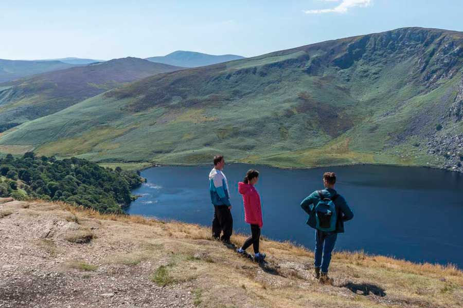 Drie wandelaars uitkijkend op een dal in Wicklow