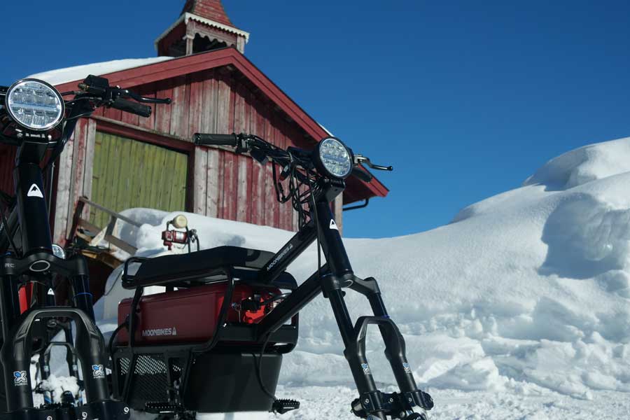 Moonbikes in de sneeuw voor een Noorse rode schuur