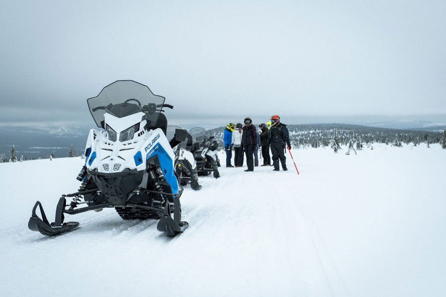 Groepje mensen op de berg naast hun sneeuwscooter