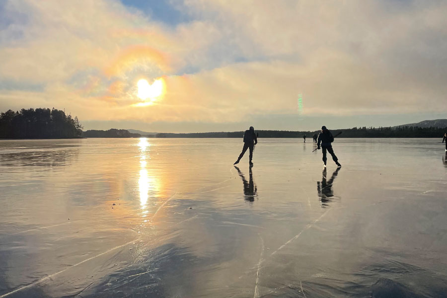 Schaatsers op het ijs in Orsa bij zonsondergang