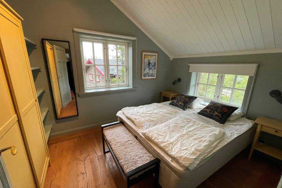 Slaapkamer met tweepersoonsbed op de bovenverdieping van Slåtterstugan